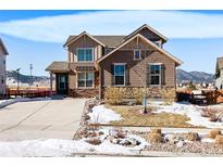Charming two-story home with stone accents and a well-maintained front yard on a sunny day at 9335 Dunraven Loop, Arvada, CO 80007