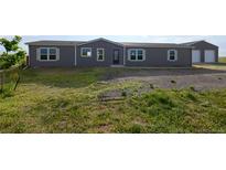Gray home exterior featuring white trim, a gravel yard, with grass and a separate garage in the background at 11595 Pass Me By Rd, Strasburg, CO 80136