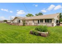 Expansive backyard featuring a well-maintained lawn and a wooden deck along the back of the house at 20995 County Road 28, Hudson, CO 80642