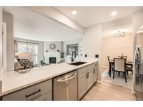 Open-concept kitchen with stainless steel appliances and views into the living room and dining area at 14602 E 2Nd Ave # 200C, Aurora, CO 80011