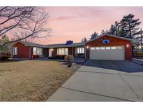 Charming brick home featuring a two-car garage with a basketball hoop above, situated on a large lot at 7420 Quaker St, Arvada, CO 80007