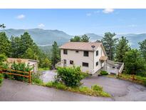 Two-story home with a surrounding mountain view, a large deck, and a two-car garage at 9189 Fallen Rock Rd, Conifer, CO 80433