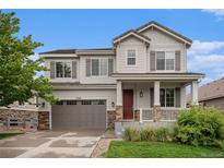 Charming two-story home with gray siding, stone accents, a covered porch, and a two-car garage at 3266 Yale Dr, Broomfield, CO 80023