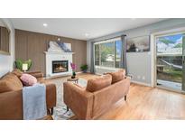 Cozy living room with a fireplace, wood-paneled accent wall, and a sliding glass door at 362 Brigitte Dr, Northglenn, CO 80260