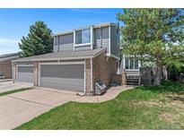 Charming two-story home with a well-manicured lawn, gray siding, brick accents, and an attached two-car garage at 3871 E Euclid Ave, Centennial, CO 80121