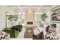 Bright living room with fireplace, hardwood floors, green velvet chairs, and access to the outside via arched glass doors at 350 Adams St, Denver, CO 80206