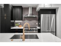 Modern kitchen boasts stainless steel appliances, stylish cabinetry, and a large island with a gold faucet at 2451 Lawrence St # 2, Denver, CO 80205