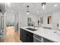Modern kitchen featuring a quartz island, stainless steel appliances, and hardwood floors at 2451 Lawrence St # 2, Denver, CO 80205