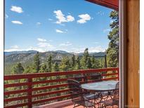 Open deck with views of mountains and trees offers a relaxing outdoor dining space at 451 Harris Dr, Idaho Springs, CO 80452