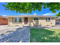 Charming one-story home with a well-maintained lawn, lovely stone walkway, and mature trees offering shade at 505 Empire St, Aurora, CO 80010