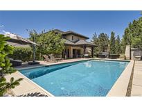 Relaxing backyard oasis with a large pool, lounge chairs, and covered patio with seating, perfect for outdoor entertaining at 9470 S Silent Hills Dr, Lone Tree, CO 80124