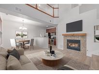 Bright living room with a cozy fireplace, TV and dining area with modern chandelier at 7777 E 23Rd Ave # 1406, Denver, CO 80238