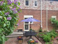Charming patio features a table, chairs, and a vibrant garden with colorful flowers at 1165 Krameria St, Denver, CO 80220