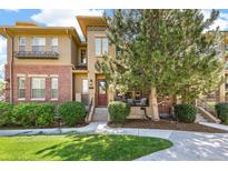 Inviting townhome featuring a well-manicured lawn, brick accents, and a charming front porch area for relaxing at 7812 Inverness Blvd, Englewood, CO 80112