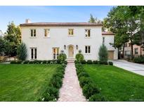 Stunning two-story home featuring a well-manicured front yard, red brick walkway, and a classic stucco facade at 181 Race St, Denver, CO 80206