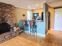 Cozy kitchen with stone fireplace, breakfast bar with seating, and stainless steel microwave at 1125 N Washington St # 501, Denver, CO 80203