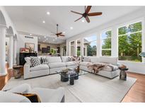 Bright living room boasts white sectional sofa, hardwood floors, and large windows showcasing the outdoor scenery at 14310 Inca St, Westminster, CO 80023
