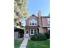 Charming two-story home featuring a stone chimney, well-manicured lawn, and inviting front entrance at 1240 S Flower Cir # A, Lakewood, CO 80232