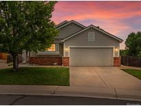 Charming single-Gathering home features a two-car garage, brick accents, a lush lawn, and mature trees at 386 Monte Vista St, Brighton, CO 80601
