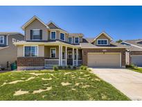 Charming two-story home with a welcoming porch and a well-maintained lawn on a sunny day at 16534 E Fire Fly Ave, Parker, CO 80134