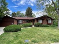 Charming single-story home with brick and wood exterior, lush green lawn, and mature trees at 12075 W 18Th Dr, Lakewood, CO 80215