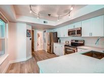 Bright kitchen features stainless steel appliances, white cabinets, and quartz countertops at 919 S Dawson Way # 14, Aurora, CO 80012
