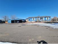 Charming home featuring a spacious carport, painted in a coordinated blue tone at 313 W 3Rd Ave, Byers, CO 80103