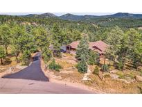 Rustic-style home nestled in a lush forest setting with a winding driveway and mountain views at 7790 S Homesteader Dr, Morrison, CO 80465