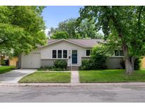 Charming single-story home featuring a well-manicured lawn, mature trees, and inviting curb appeal at 6402 Iris Ct, Arvada, CO 80004