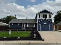 Two-story home with a blue exterior, landscaping, and a two-car garage at 2670 S Hooker St, Denver, CO 80219