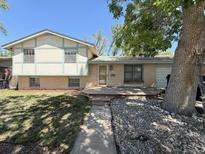 Charming home featuring a brick facade, a wooden porch, mature trees, and easy access via the concrete walkway at 7195 E Louisiana Ave, Denver, CO 80224