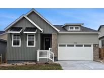 Charming home featuring a two-car garage, stone accents, gray siding, and stylish black window awnings at 17146 W 92Nd Loop, Arvada, CO 80007