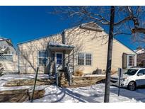 Tan exterior home with blue accents, steps, and a small yard in the winter at 1869 S Union Blvd, Lakewood, CO 80228