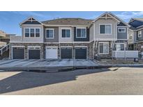 Modern townhome exterior with gray siding, stone accents, and individual garages, showcasing contemporary design at 23688 E Ida Dr # E, Aurora, CO 80016