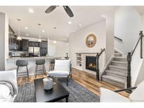 Bright living room featuring a fireplace with stone surround, open to the kitchen and staircase at 8183 S Yosemite Ct, Centennial, CO 80112
