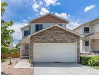 Charming two-story home with a stone-accented garage and well-maintained lawn under a cloudy sky at 8065 Clay St, Westminster, CO 80031