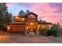 Stunning craftsman home with an attached garage, stone accents, a charming front porch and beautiful outdoor lighting at 394 S Ponderosa Way, Evergreen, CO 80439