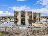 High-rise apartment building with a parking lot and bare trees in the foreground on a sunny day at 7865 E Mississippi Ave # 907, Denver, CO 80247