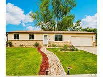 Charming single-story home with a well-manicured lawn, rock pathway, and mature trees under a sunny blue sky at 7075 Welch Ct, Arvada, CO 80004