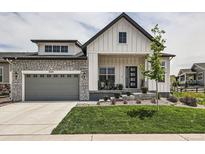 Charming two-story home with a combination of stone and white siding and a well-manicured lawn at 5668 Shadescale Way, Castle Rock, CO 80104