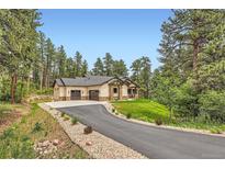 Sprawling ranch-style home with a three-car garage, stone accents, and private drive surrounded by lush trees at 8280 Bannock Dr, Larkspur, CO 80118