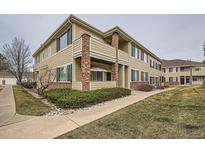 Two-story exterior elevation with light yellow siding, stone accents, and a well-maintained landscape at 16828 E Gunnison Dr # 7H, Aurora, CO 80017