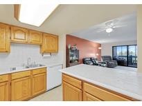 Bright kitchen featuring wood cabinets, white countertops, and appliances open to the living room at 14001 E Marina Dr # 607, Aurora, CO 80014