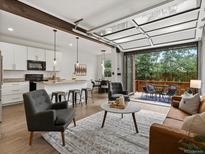 Bright living room with modern kitchen, garage door-style opening to a patio, and contemporary furnishings at 11719 W 45Th Pl, Wheat Ridge, CO 80033