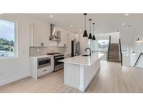Bright modern kitchen boasts stainless steel appliances, an island, and sleek minimalist finishes at 10157 W 38Th Ave, Wheat Ridge, CO 80033
