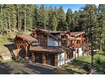 Beautiful exterior view of rustic home with log accents, stone, and an attached two car garage at 4560 Hilltop Rd, Evergreen, CO 80439