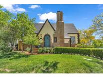 Charming home featuring a lush front lawn, brick chimney, and a distinctive arched front door at 1300 Cherry St, Denver, CO 80220