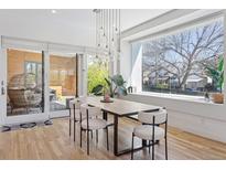 Bright dining room featuring a modern table with stylish chairs and a window overlooking greenery at 1801 W 33Rd Ave, Denver, CO 80211