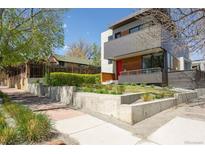 Modern home featuring layered landscaping, concrete retaining walls and a red front door on a tree-lined street at 1801 W 33Rd Ave, Denver, CO 80211