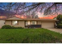 Charming single-story home with well-manicured lawn and mature trees under a colorful sunset at 726 Mobile St, Aurora, CO 80011